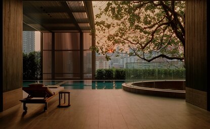 Swimming pool at Aman Nai Lert Bangkok overlooking manicured gardens at dusk.