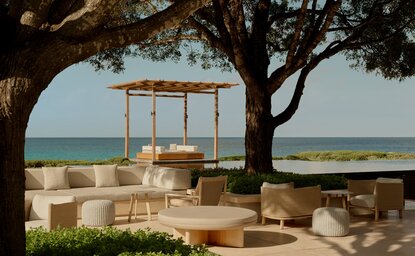 Bar seating area overlooking the ocean at Amanyara resort, Turks & Caicos, with wooden pergola and cushioned seating.