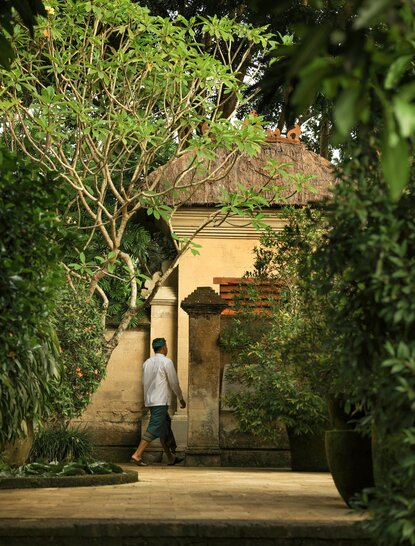 Stone archway entrance to a villa at Amandari, Indonesia, with climbing vines and tropical foliage.