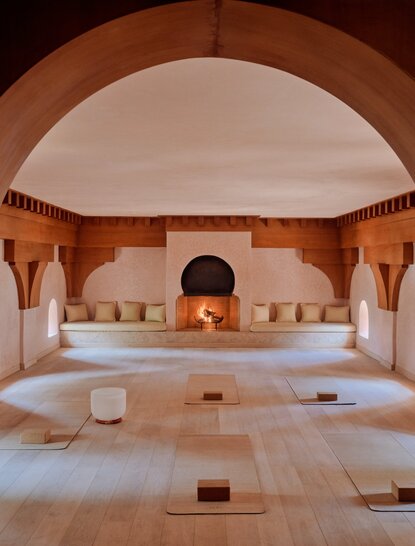 Studio de yoga à l'Amanjena, avec sol en pierre, arches en terre cuite et mobilier minimaliste.