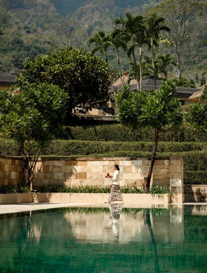 Plunge pool at Amanjiwo resort overlooking terraced landscapes and palm trees in Java, Indonesia.
