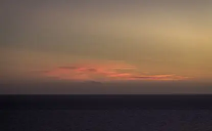 Sunset over the horizon at Amanvari, Mexico, with warm amber and rose tones reflecting across a darkening landscape.