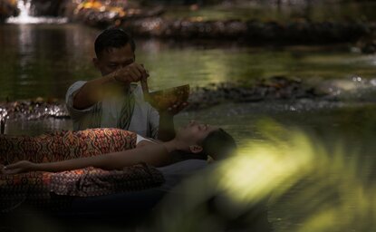 Floating soundbath at Amanwana, Indonesia, with glowing waters and natural rock formations at dusk.