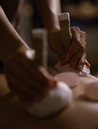 Therapist's hands performing a grounding massage treatment at Amanwana, Indonesia.