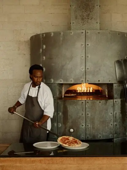 Chef tending wood-fired oven at Amanyara beach club restaurant, Turks and Caicos.