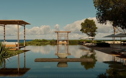 Wooden pavilions reflected in still water at Amanyara's main pool, Turks and Caicos.
