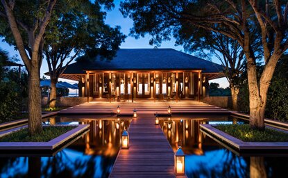 Amanyara five-bedroom villa at dusk, illuminated with warm lighting and reflecting in still water channels.