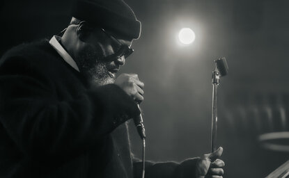 Jazz musician performing at Aman New York, singing into microphone in black and white.