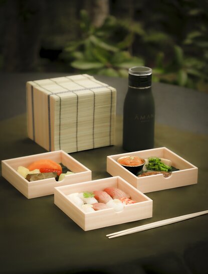 Wooden picnic lunchbox with compartments filled with sushi and fresh ingredients at Aman Kyoto.