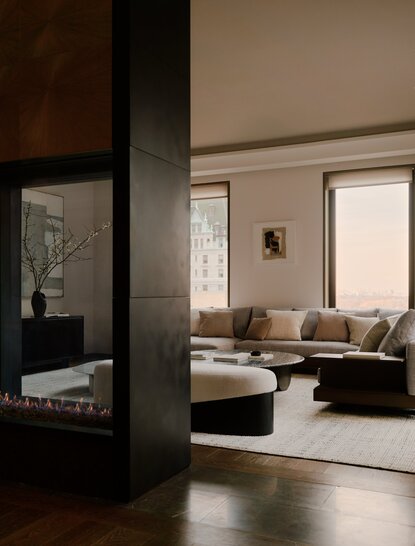 Sala d'attesa moderna con colonne scure e sedute in tonalità neutre presso Aman New York.