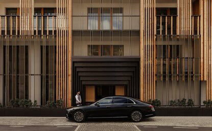 Main entrance to Aman Rosa Alpina in Italy, with a dark car parked before ornate wooden doors.