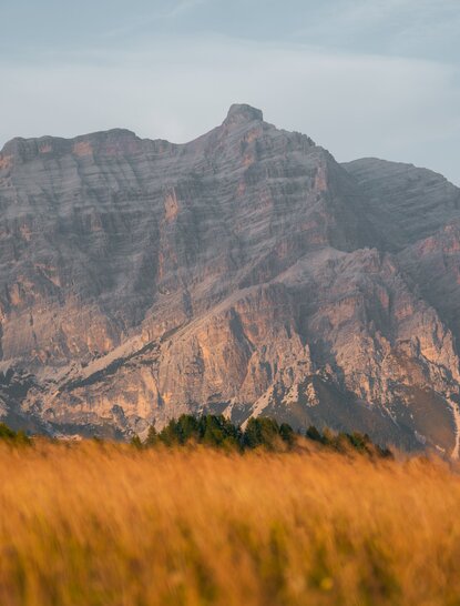 Montagna rocciosa con pendici dorate al tramonto, vista dal resort Aman Rosa Alpina in Italia.