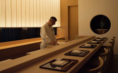 Aman Tokyo – Musashi dining venue, chef preparing dishes at counter with minimalist wooden interior.