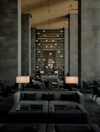 The Lounge at Aman Tokyo, a serene dining space with slate walls, lit candles, and minimalist furnishings.