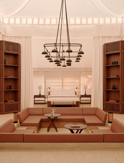Grand tented pool pavilion at Aman-i-Khas, India, with chandelier and symmetrical wood furnishings.