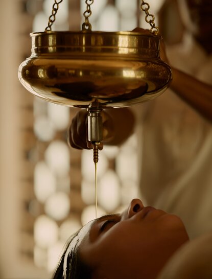 Brass oil lamp suspended from chain at Amanbagh wellness spa.