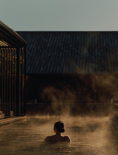 Solitary bather in steaming onsen at Amanemu, Japan, at dusk.