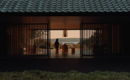 Amanemu's welcome pavilion with wooden sliding doors opening onto a serene courtyard at dusk.