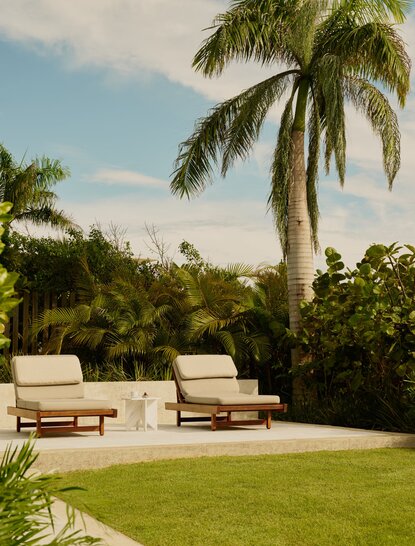 Sunlit casita garden at Amanera with loungers beneath palm trees and manicured lawn.