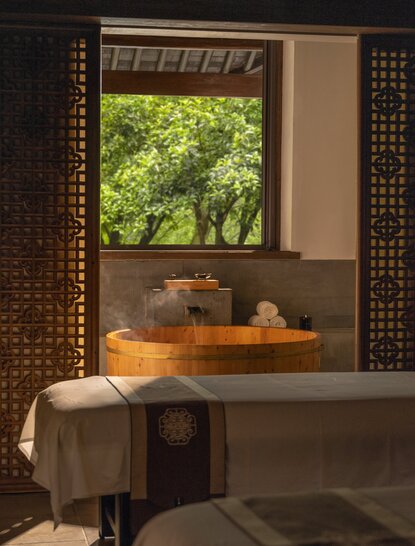 Wooden shelf holding spa products beside a window overlooking greenery at Amanfayun's spa and wellness retreat.