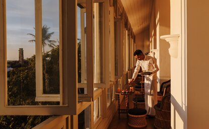 Sunset light warms a colonnaded balcony at Amangalla, with views across Sri Lanka's landscape beyond.