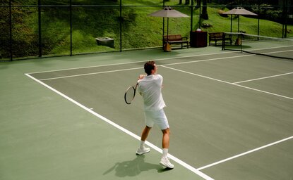 A model playing tennis on the court at Amanpuri, Thailand.