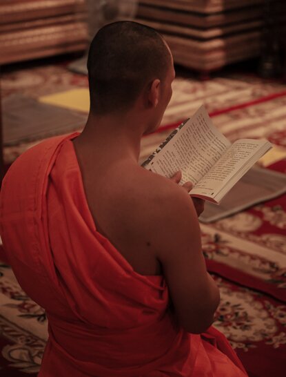 Buddhist monk in red robes meditating at Amantaka temple in Laos.