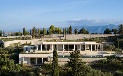 Villa with colonnade overlooking olive groves and mountains at Amanzoe resort, Greece.