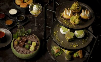 アマン東京のラウンジで、緑色の調度品に囲まれた様々な料理とドリンクが並ぶ。