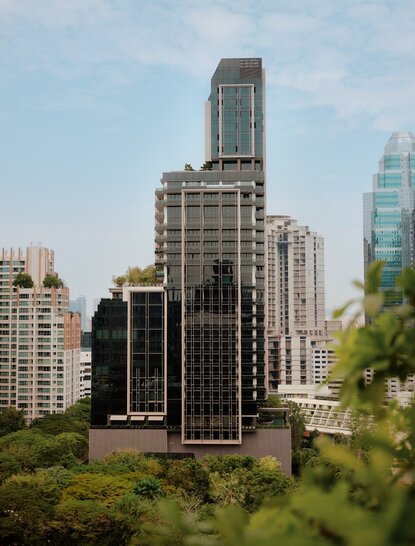 Aman Nai Lert Bangkok's exterior amongst the city's architectural landscape and riverside greenery.