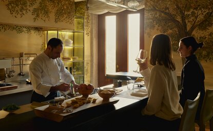 Chef preparing dishes in Palazzo Kitchen at Aman Venice, whilst diners observe.