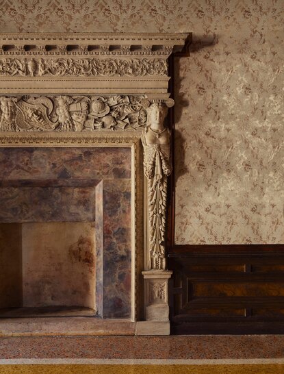 Ornate fireplace with carved stone detailing in a suite at Aman Venice, Italy.
