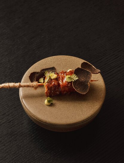 Skewer with roasted vegetables on a beige plate at Aman Venice hotel.