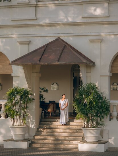 Amangalla exterior entrance with colonial archway, dark canopy and potted greenery flanking the doorway.