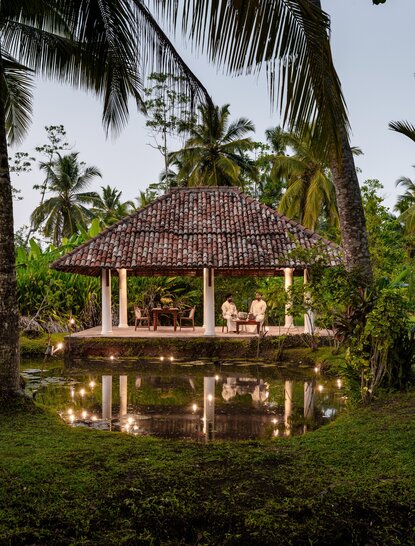 Candlelit pavilion at Amangalla illuminated amongst tropical gardens at dusk, Sri Lanka.
