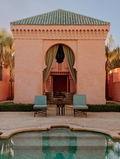 Amanjena pavilion exterior with Moroccan arched doorway, plunge pool and turquoise seating.