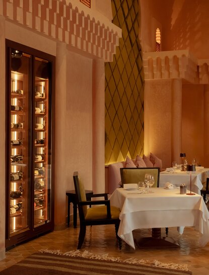 Dining venue at Amanjena resort with warm terracotta walls, ornate wooden doors and traditional Moroccan architectural details.