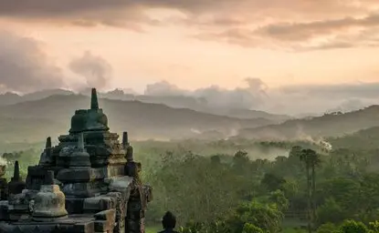 Amanjiwo temple overlooks mist-covered Kedu Valley at dawn, surrounded by verdant hills.