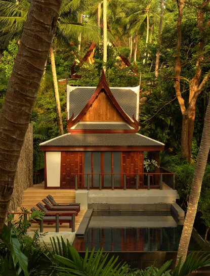 Amanpuri spa treatment room with pitched roof nestled among tall trees at dusk, Thailand.