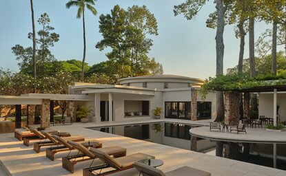 Amansara's main pool area with dining room and loungers beneath tall palms, Cambodia.