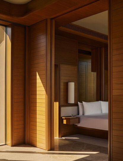 Wooden-framed entrance to an Estuary Casita at Amanvari, Mexico, with warm sunlight streaming across the threshold and a glimpse of the principal bedroom beyond.
