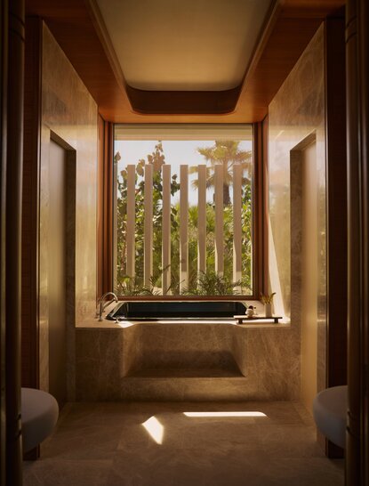 Bathroom in a Horizon Casita at Amanvari, Mexico, with a deep soaking tub positioned beneath a window framing views of desert landscape and cacti.