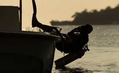 Silhouetted diver preparing to descend from the Aman XVII boat at Amanwana, Indonesia.