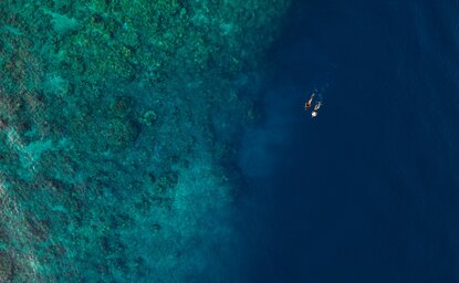 Snorkeller in clear waters off Amanwana, Indonesia, aerial view.