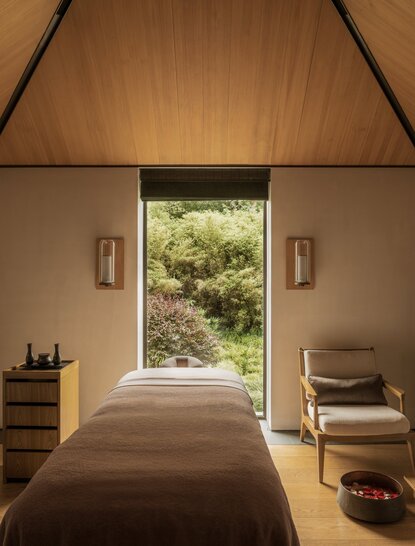 Spa treatment room at Amanyangyun with open doors framing a garden view, wooden furnishings and neutral tones.