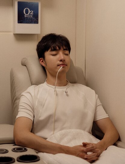 Woman seated in mild hyperbaric oxygen chamber at Amanyangyun spa wellness facility, China.