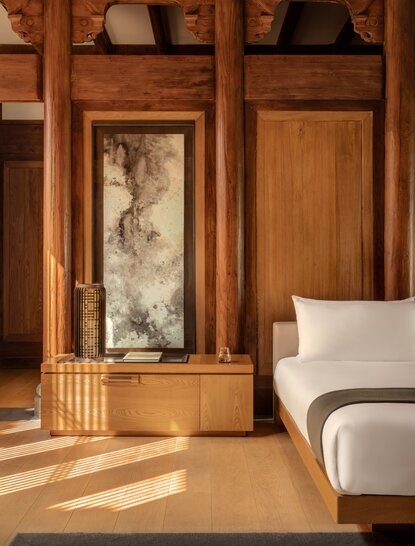 Wooden wardrobe with silk panel beside a bed in an Amanyangyun villa bedroom.