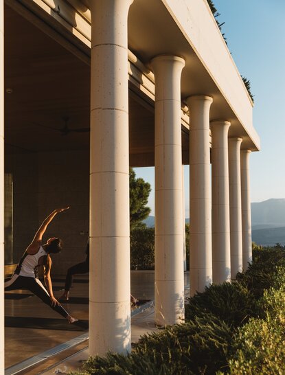 Columned terrace at Amanzoe resort with mountain views beyond, Greece.