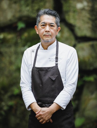 Hiroyuki Matsuo, Executive Pastry Chef at Aman Kyoto resort, stands in portrait wearing a white shirt and dark apron.