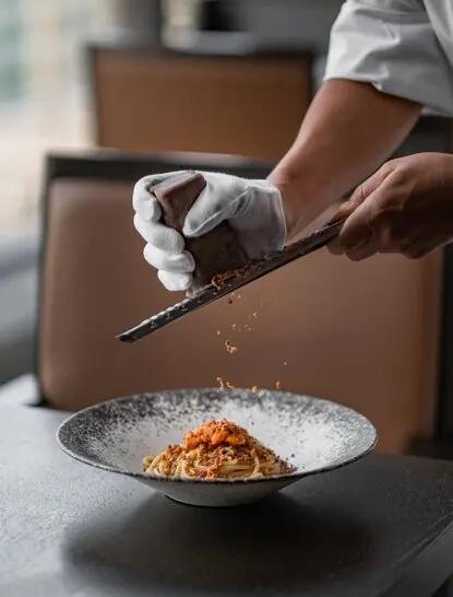 Chef grating ingredient over plated dish at Aman Tokyo.